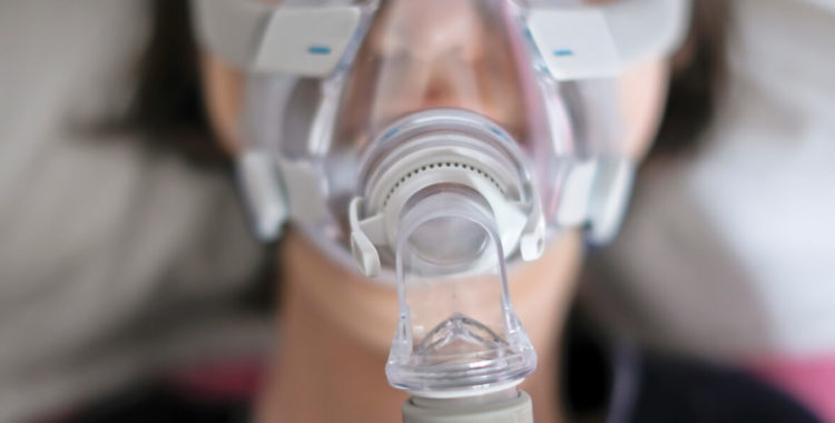 A woman sleeping in her bed with a ventilator
