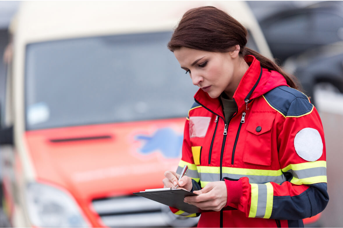 Concetrated female paramedic in uniform writing in clipboard
