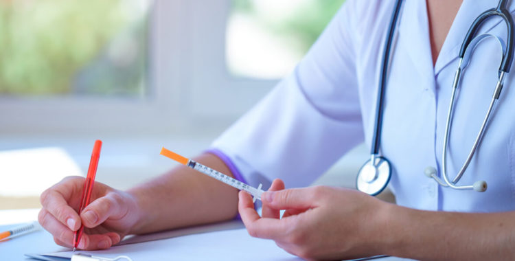Doctor writes medical prescription for insulin injection