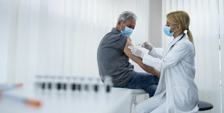 elderly man getting vaccine shot by doctor epidemiologist