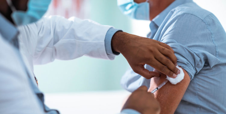 Mature man taking a vaccine from his doctor