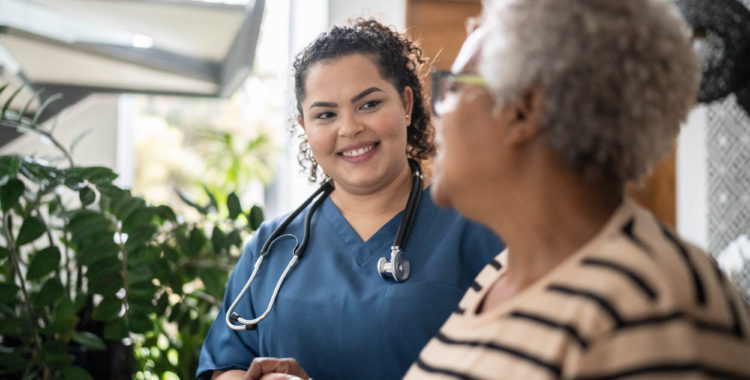 Home caregiver helping senior woman walking at home
