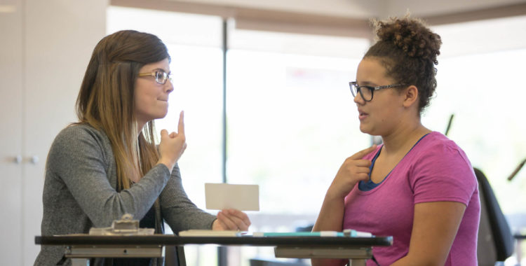 Female speech therapist helping a teenage patient inside of a clinic