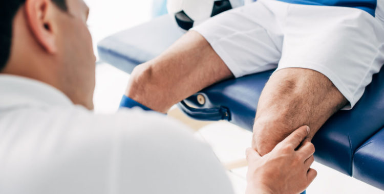 Physiotherapist massaging leg of football player