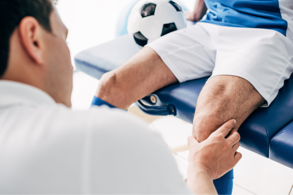 Physiotherapist massaging leg of football player