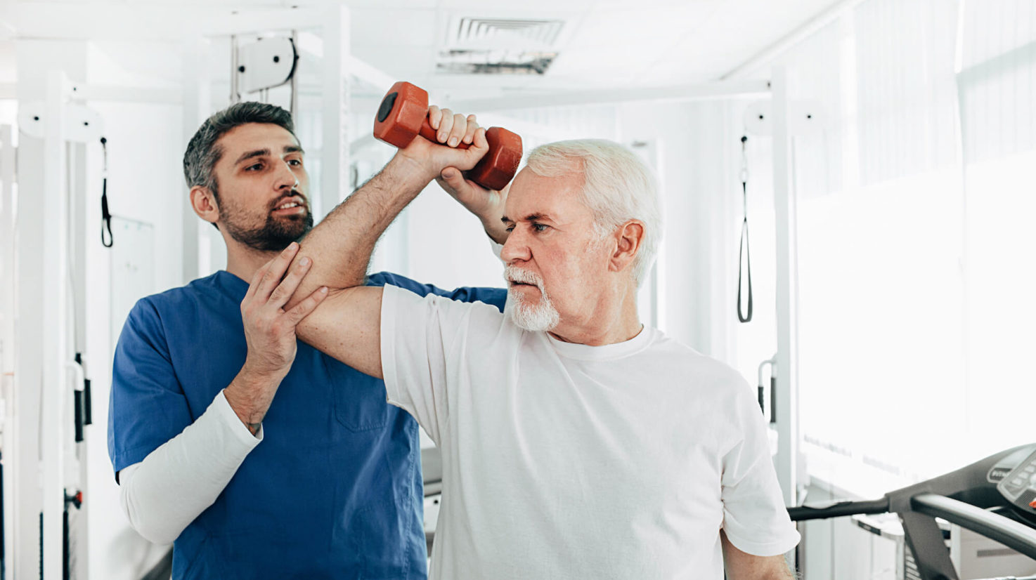 senior man lift a dumbbell, he doing treatment exercise with his physiotherapist. Physio treatment at rehab center