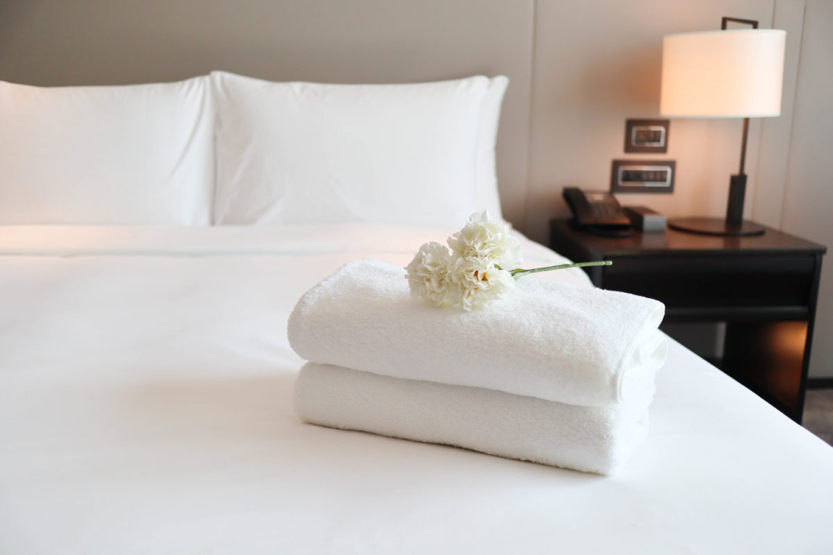 Clean white bath towels on the neatly clean bedroom – coziness and clean concept
