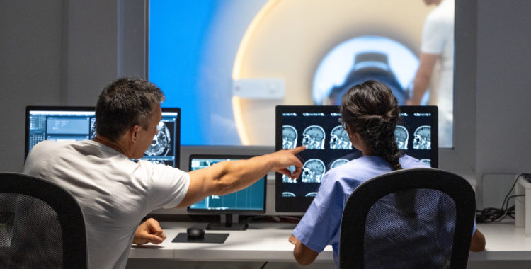 Two MRI radiologists sitting in the control room and operating the MRI scanner