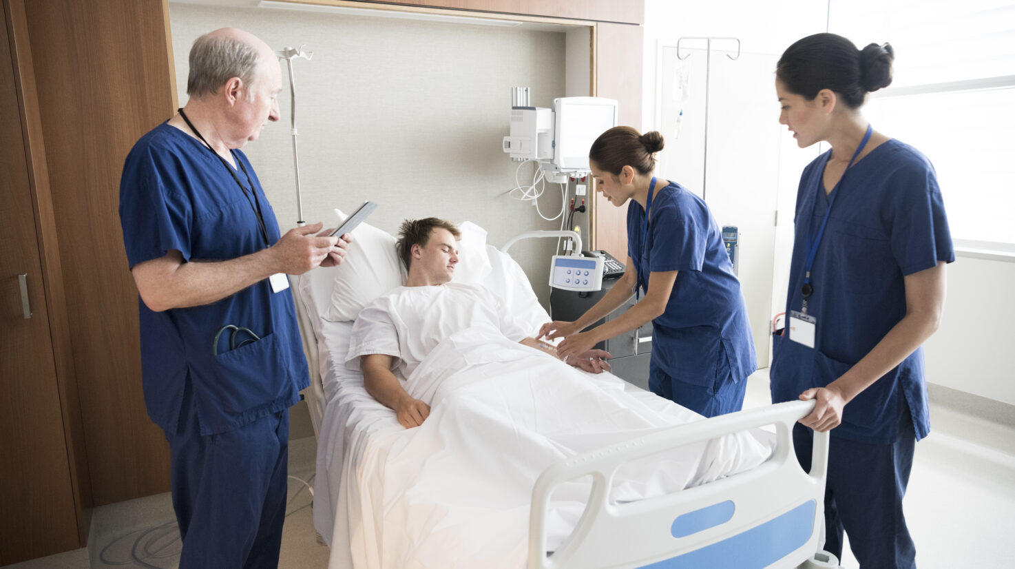 Medical team treating male patient in hospital bed