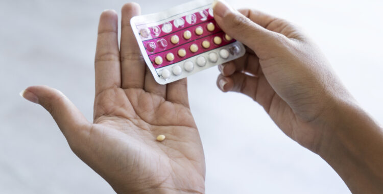 Woman holding birth control pills at home