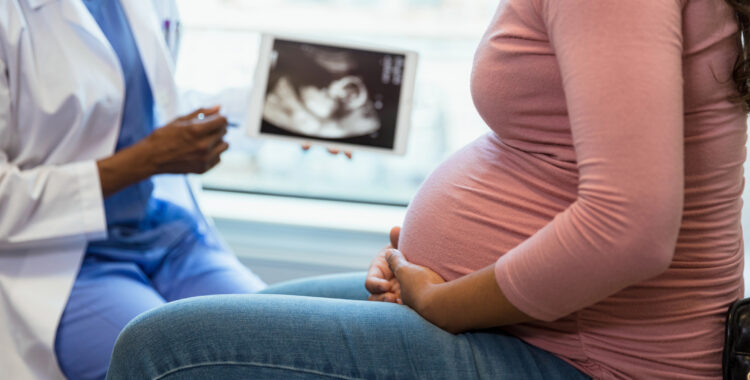 Focus on foreground as doctor shows ultrasound in background