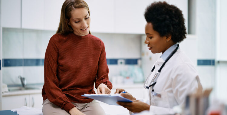 Happy woman going through her medical data with black female doctor at the clinic.