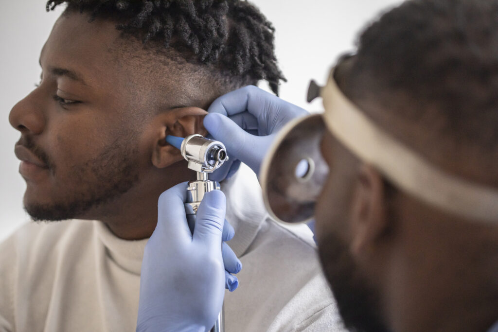 Close-up of a male doctor carefully holding the patient's ear to see more clearly inside his ear to see if he needs a hearing aid in a modern clinic, otolaryngology department