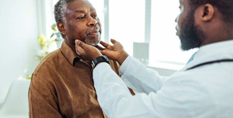 Doctor doing throat examination on older man