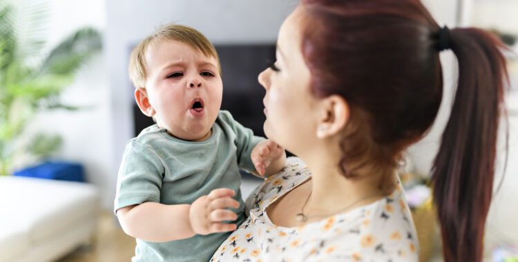 mother holding child baby on the living room. The baby is sick having some cough