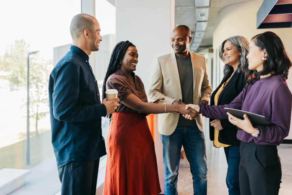 Group of multiracial business partners shaking hands in coworking office space
