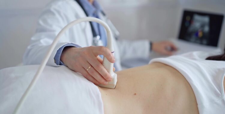 Doctor man using ultrasound equipment on the back of a patient, woman analyzing the results on a monitor in the background. Medicine and science