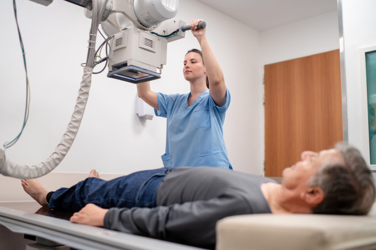 Technician conducting X-ray of senior patient’s leg