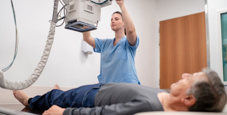 Technician conducting X-ray of senior patient’s leg