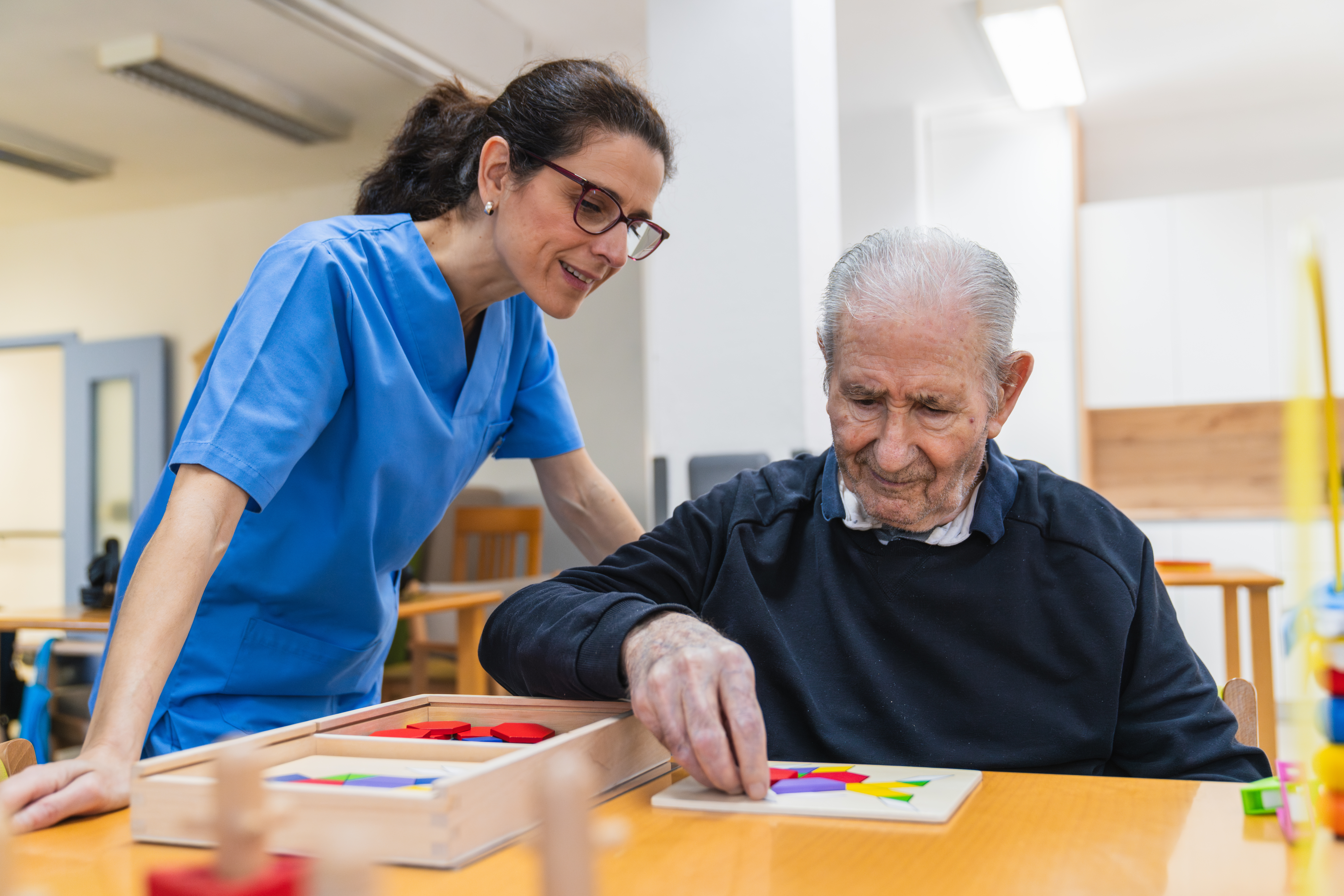 Caring nurse assisting senior man in nursing home