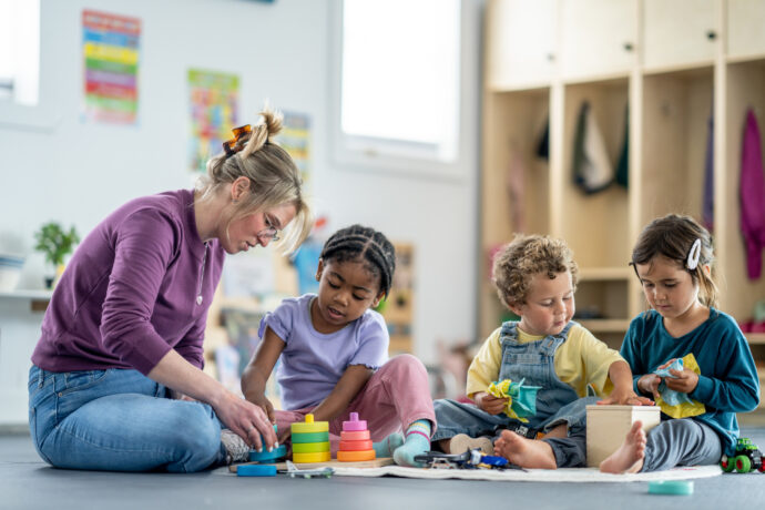 Group of Young Children Learning with Teacher in Colorful Daycare Classroom