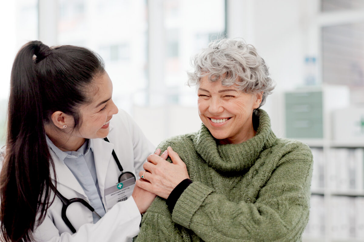 Happy, care and face of a doctor with a woman for medical trust, healthcare and help. Laughing, hug and portrait of a young nurse with a senior patient and love during a consultation at a clinic