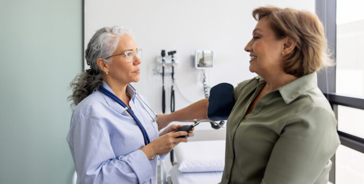 Doctor checking the blood pressure on a woman in the examination room