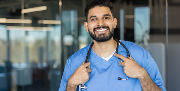 Indian doctor smiling, wearing scrubs and stethoscope
