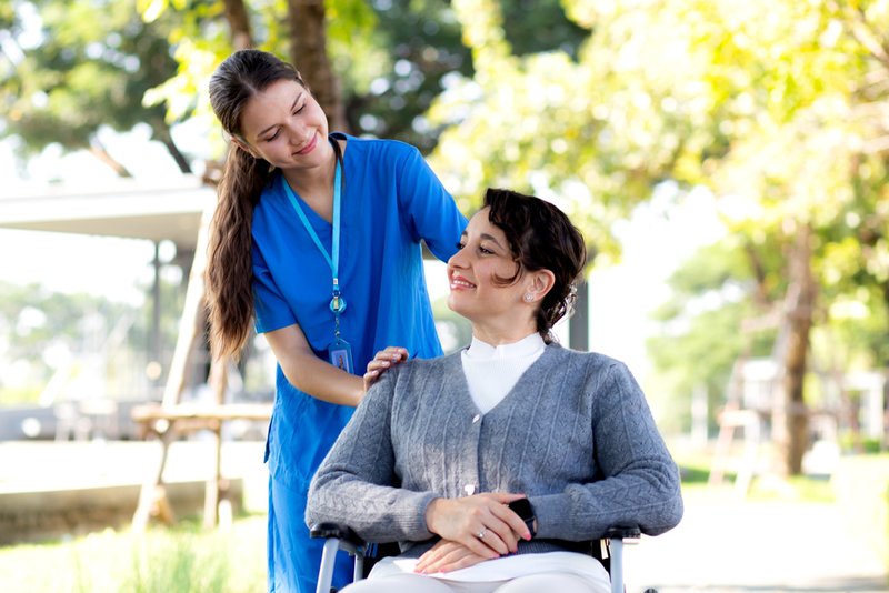 Young female nurse with female patient recovering at home after surgery