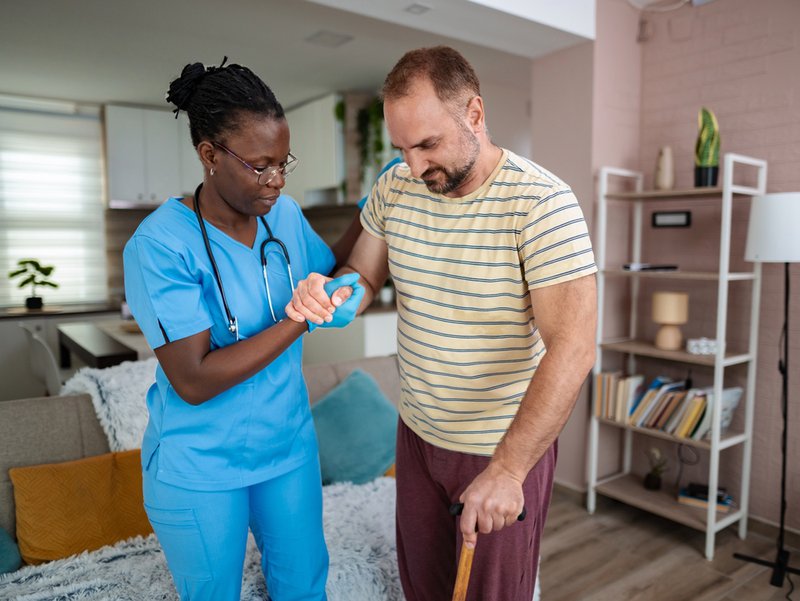 Female nurse supporting man with mobility issues