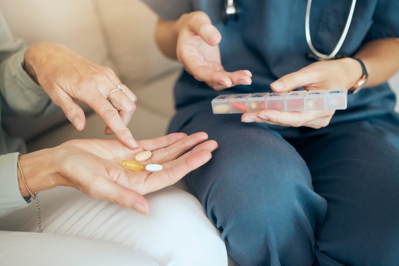 Home health nurse helping patient with taking meds