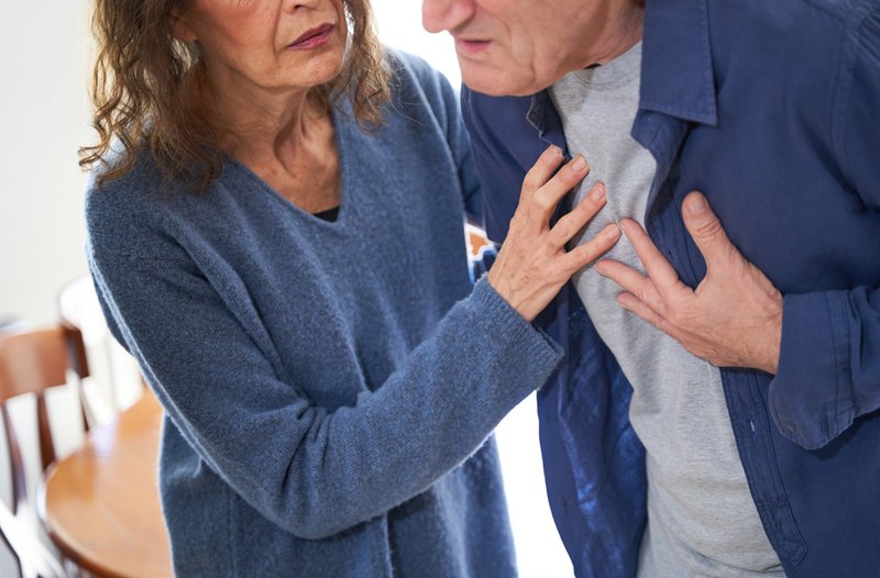 Elderly couple, wife supporting husband with visible chest pains