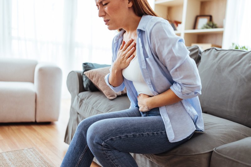 Woman holding chest, wondering if she's having heartburn or acid reflux