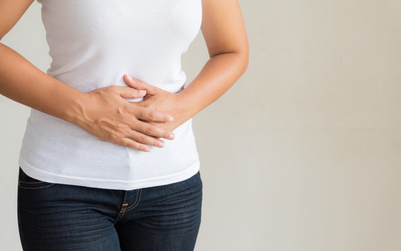 Woman holding her stomach to show underlying digestive conditions
